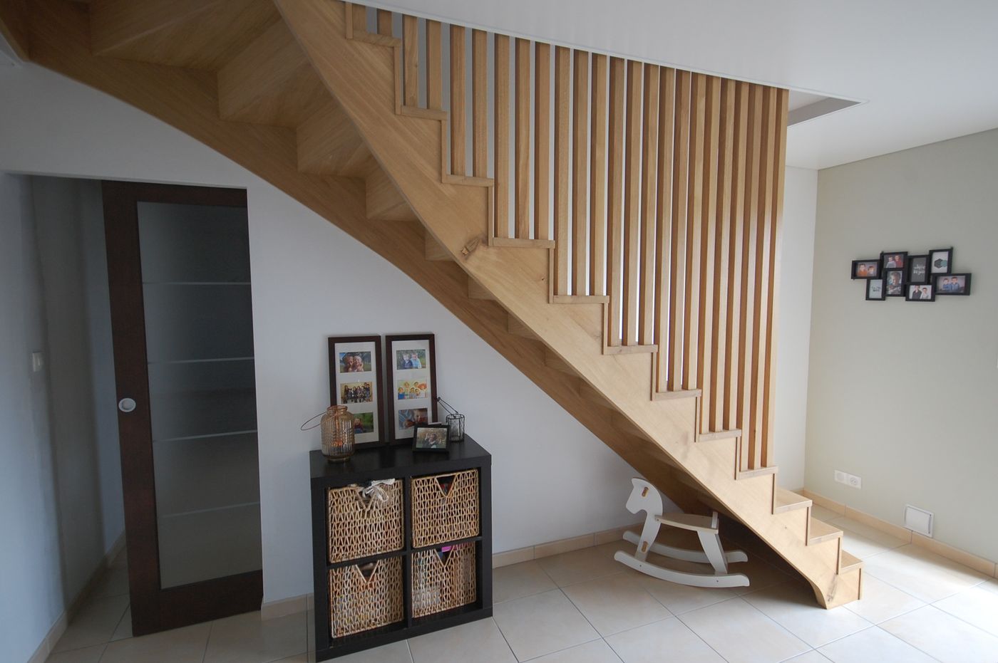 Escalier bois clair avec claustra de barreaux verticaux dans une pièce à vivre