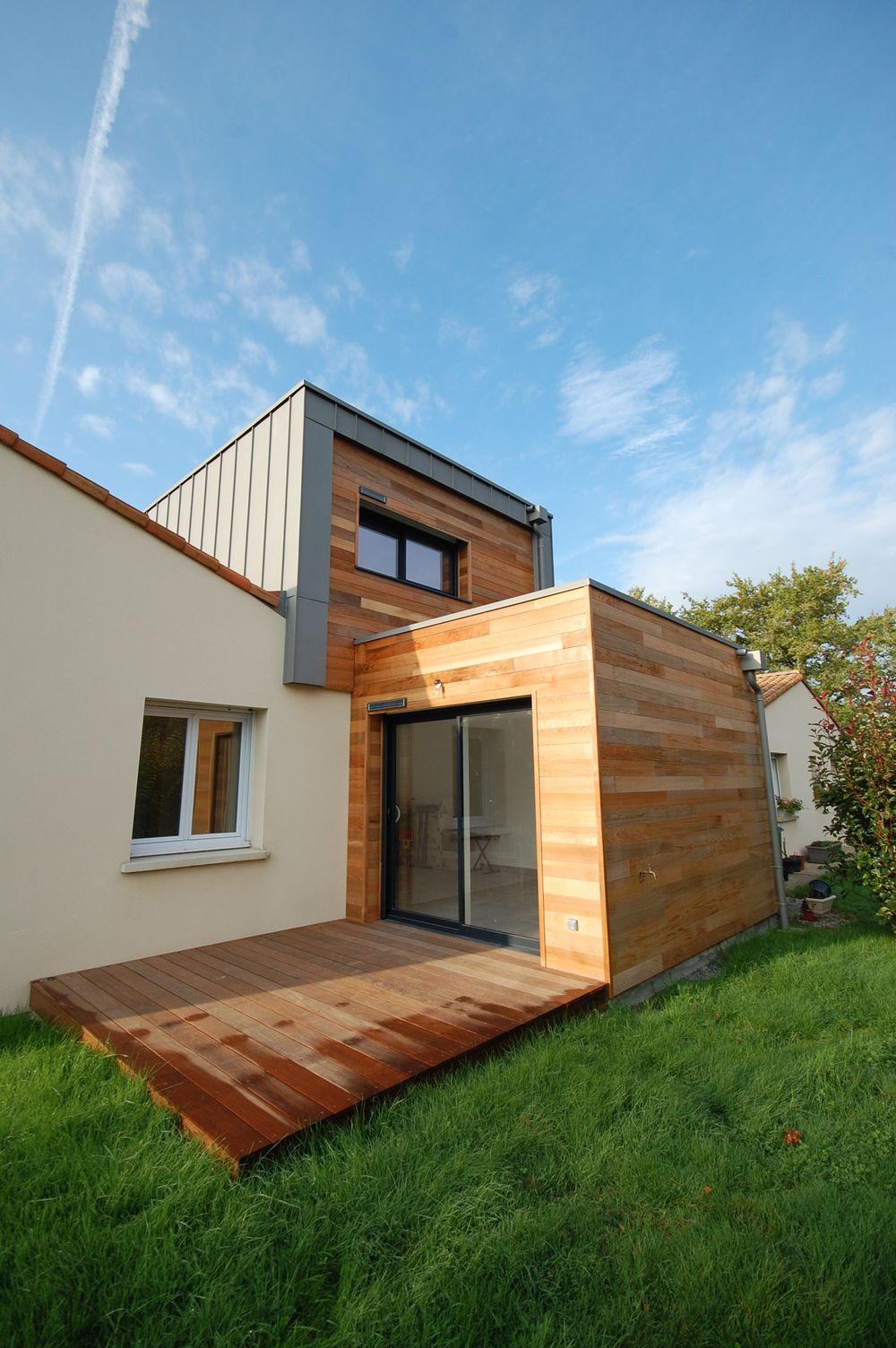 Extension cubique en bardage bois prolongée par une terrasse en lames